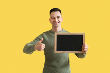 Male teacher with chalkboard showing thumb-up on yellow background