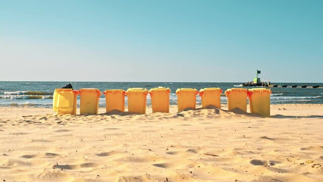 Row of Plastic Garbage Bins Deployed on Seashore Beach Sand