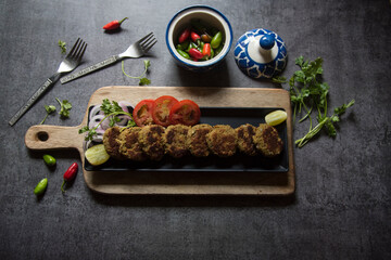 Top view of shami kebab and vegetables on a tray, with use of selective focus