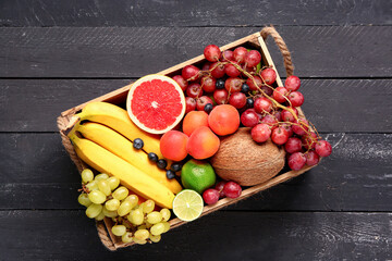 Box with different fresh fruits on black wooden background