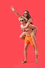 Young couple in sunglasses on red background