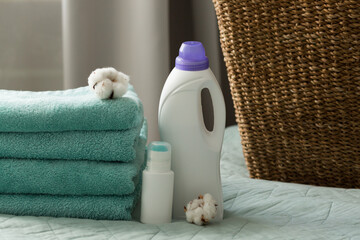 White plastic packaging with laundry detergent, liquid washing powder, conditioner, bleach, stain remover for clothes, terry towels and cotton flowers.