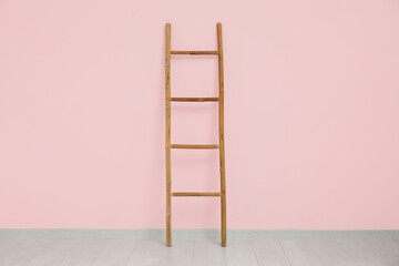 Wooden ladder near pink wall in room