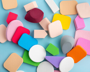 Heap of colorful cosmetic sponges on blue background. Top view