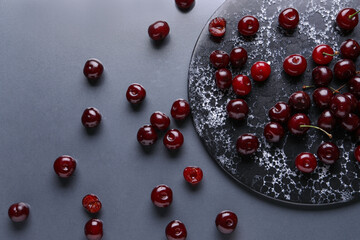 Board with sweet cherries on grey background