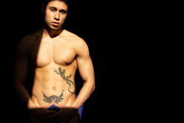 A young attractive guy with a handsome body posing under the sun in the studio.