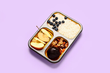 Lunchbox with tasty food on lilac background