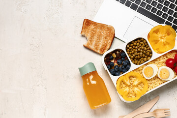 Laptop, bottle of juice and lunchbox with tasty food on white background