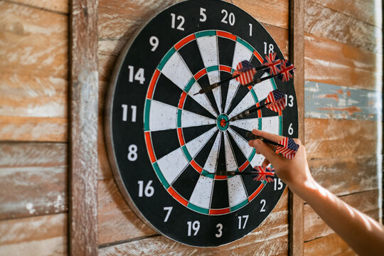 Game of darts. Close-up female hand pulls a dart from a target.