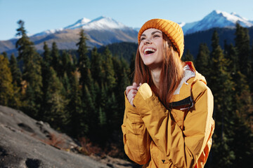 Woman smile with teeth happiness and laughter tourist in yellow raincoat travel in the fall and hiking in the mountains in the sunset sunshine freedom