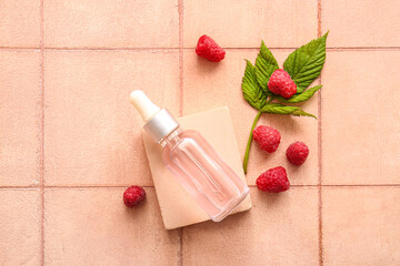Decorative podium with bottle of cosmetic raspberry oil on pink tile background