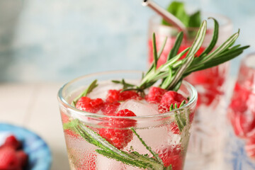 Glass of fresh raspberry lemonade with rosemary on blue background, closeup