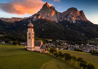 Seis am Schlern, Italy - St. Valentin Church and famous Mount Sciliar mountain with colorful clouds, blue sky and warm sunlight at South Tyrol on a summer afternoon