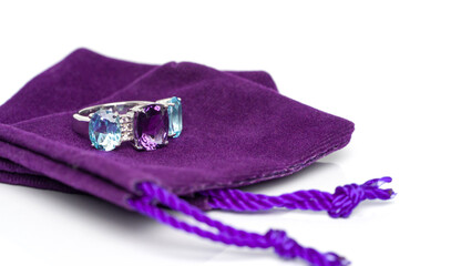 Amethyst with blue topaz and white sapphire jewel or gems ring on violet velvet bag. Collection of...