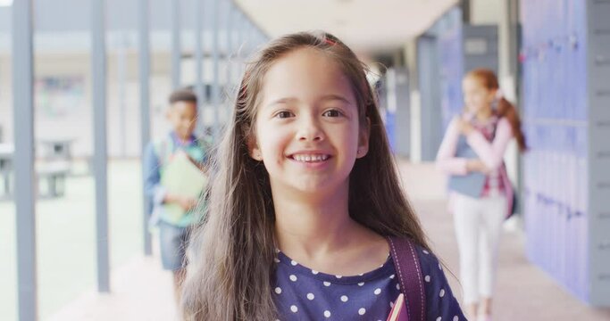 Portrait of happy caucasian schoolgirl walking in school corridor
