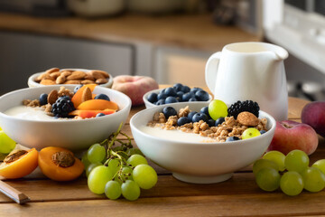 Two healthy breakfast bowl with granola fruits Greek yogurt and berries on wooden table in a rustic...