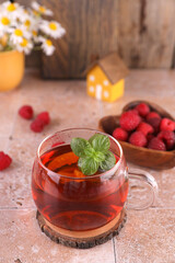 Tea with mint and raspberries in a transparent mug