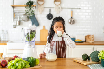 Obraz na płótnie Canvas Portrait of enjoy happy little asian child girl smiling having protein breakfast drinking and hold glasses of fresh milk,healthy nutrition,calcium and vitamin,dairy product,strong, growth in kitchen