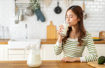 Obraz na płótnie Canvas Portrait of beauty healthy asian woman smiling and having protein breakfast drinking and hold glasses of milk of fresh milk, nutrition,calcium and vitamin,dairy product in kitchen at home.Diet concept