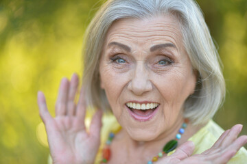 Close up portrait of happy older woman standing outside in summer