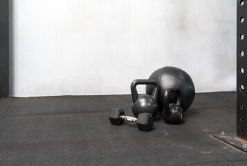 A sturdy iron kettlebell and a set of dumbbells are on the gym floor. Their robust metal bodies are...