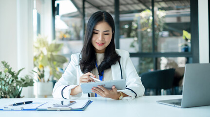 businesswomen sit at their desks and calculate financial graphs showing results about their...