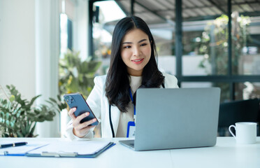 businesswomen sit at their desks and calculate financial graphs showing results about their...
