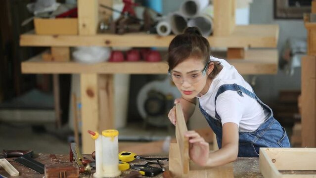 A carpenter works with equipment on a wooden table in a carpentry shop.
