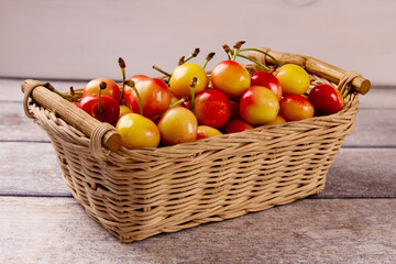 Yellow fresh cherry  in a basket against a gray wooden background.