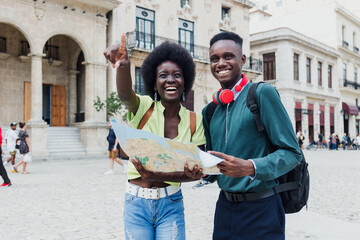 Young afro american couple tourist looking a map while on vacation during summer together in Latin...