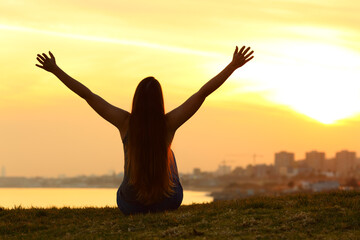 Silhouette of a woman celebrating at sunset in outskirts