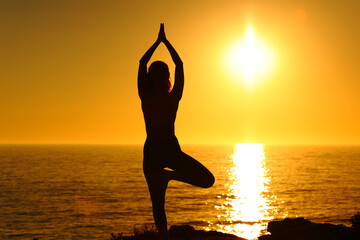 Yogi exercising yoga at sunset on the beach