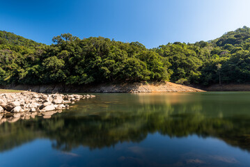 Day shot of reservoir with water reflection of tree and sky