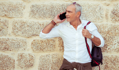 Fototapeta na wymiar smiling mature man talking on phone in the street
