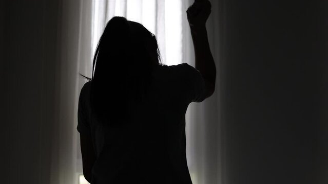 Silhouette of a depressed woman hurt yourself in a dark room.  Domestic violence. Family problems. Stress. Violence. Depression and suicide concept.
