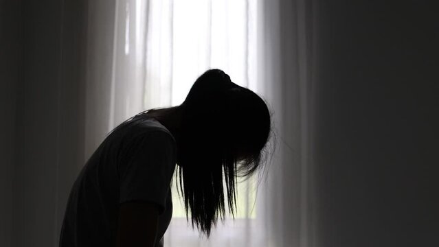 Silhouette of a depressed woman hurt yourself in a dark room.  Domestic violence. Family problems. Stress. Violence. Depression and suicide concept.