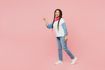 Full body fun young woman of African American ethnicity wear white sweatshirt casual clothes walk go point index finger aside on area isolated on plain pastel light pink background. Lifestyle concept.