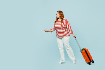 Traveler chubby overweight woman wears casual clothes hold bag walk go isolated on plain blue...
