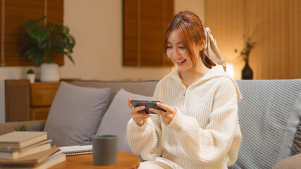 Home lifestyle concept, Young woman playing game on smartphone with excited in night time at winter