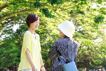シニアの女性と娘が仲良く会話。自然の中で観光、散歩イメージ
