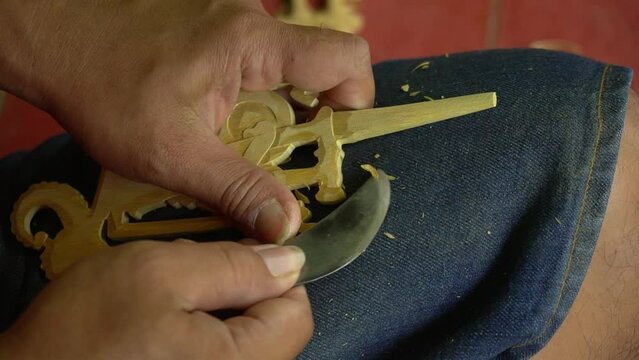 The process of carving dolls made of wood, all done handmade using a small knife. Javanese traditional wooden puppet making by professional craftsmen. Shot up close and slow motion