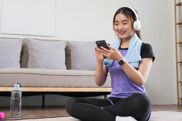 Young asian woman wear headphone to surfing internet and listens music on smartphone after exercise