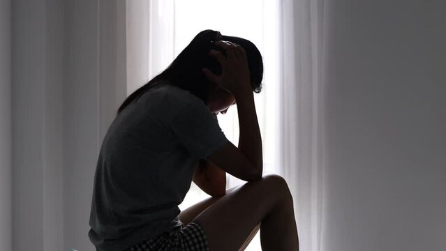 Silhouette of depressed woman sitting on the floor of an abandoned building Sad woman, Cry, drama, lonely and unhappy concept.