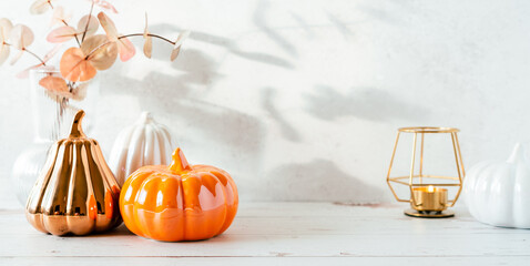 Details of Still life, pumpkins, candle, brunch with leaves on white table background, home decor in a cozy house. Autumn weekend concept. Fallen leaves and home decoration