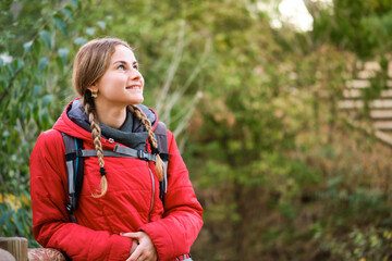 Smiling young female hiker resting and contemplating views in the forest.