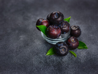 Sweet plums on dark background. Fresh blue plums with leaves. Food fruit Background. Summer postcard. Harvesting in garden, Harvest of plum