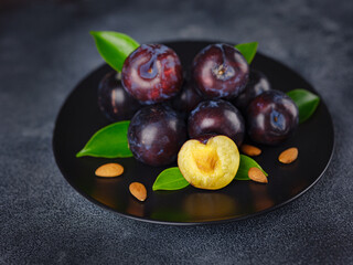 Sweet plums on dark background. Fresh blue plums with leaves. Food fruit Background. Summer postcard. Harvesting in garden, Harvest of plum