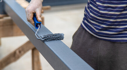 A man paints a metal pole. Selective focus.