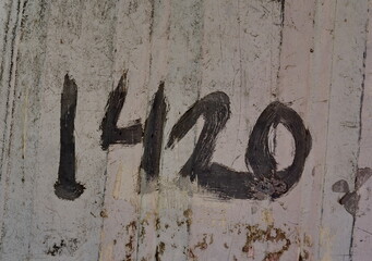 Numéro 1420. Chiffre peint en gris sur mur sali. Numéro de rue. 