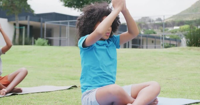 Video of diverse schoolgirl and schoolboy practicing yoga meditation in outdoor class, copy space